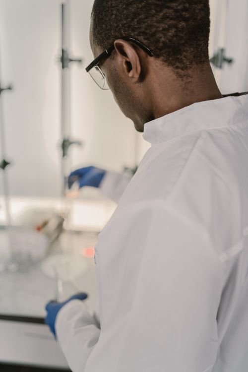 Free Research scientist in lab coat conducting experiments in a laboratory setting, focused on chemical reactions. Stock Photo