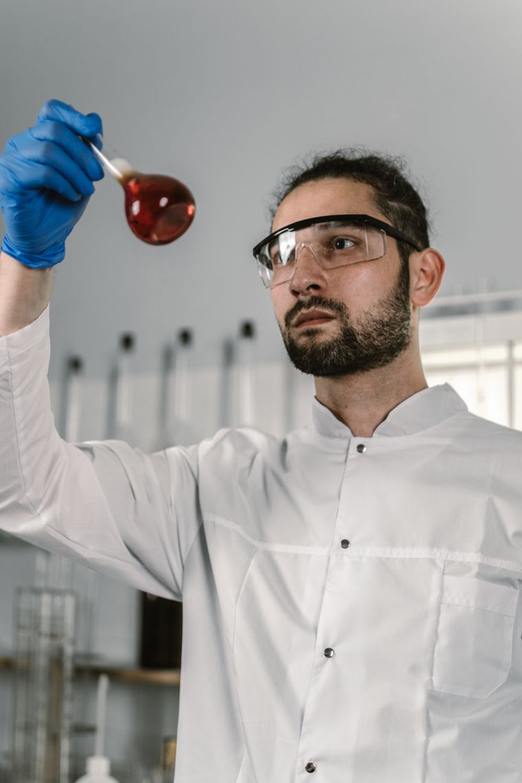 A scientist examining a volumetric flask under laboratory light