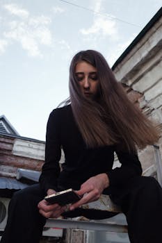 A young woman with brunette hair uses a smartphone outdoors. Low angle shot.