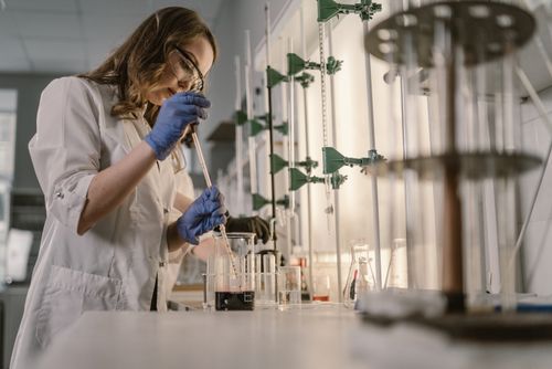 Free Female scientist performing an experiment in a laboratory setting with lab equipment and safety gear. Stock Photo