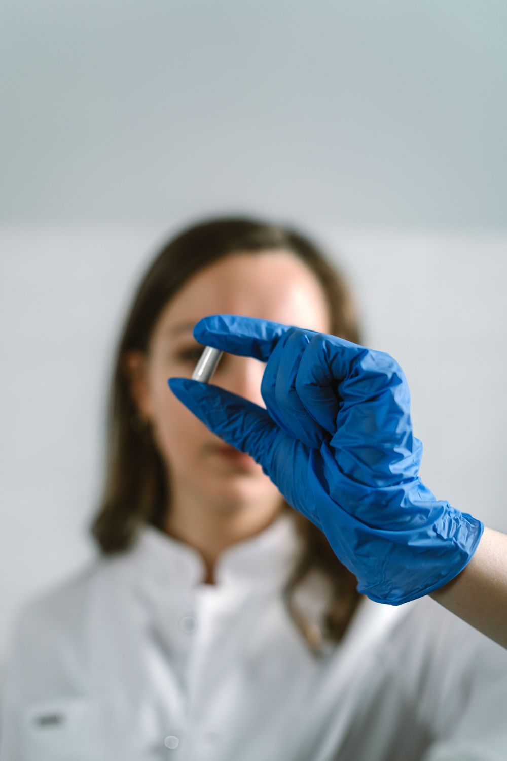 Pharmacist in a blue glove holding a tablet