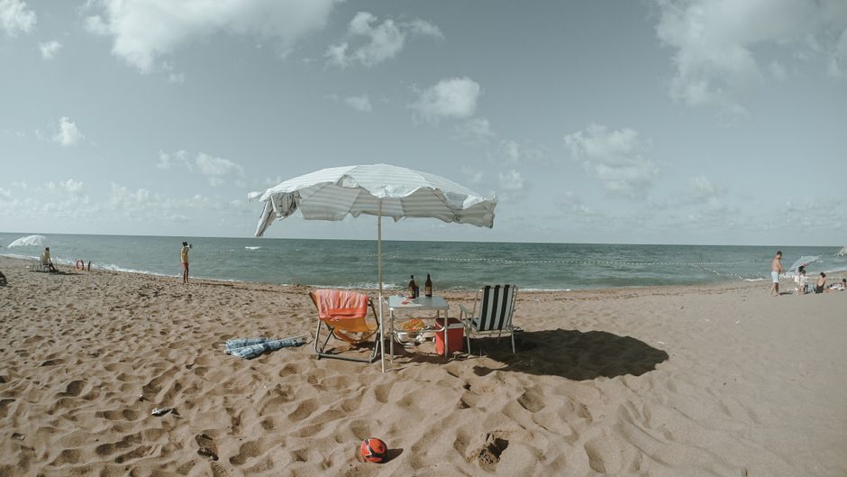 Sunscreen and a reusable water bottle on a beach in Sarandë, Albania, emphasizing hydration and sun protection