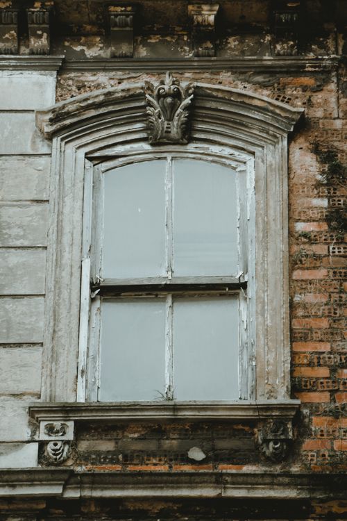 Free Close-up of an ornate vintage window set in weathered brick, showcasing classic architectural design. Stock Photo
