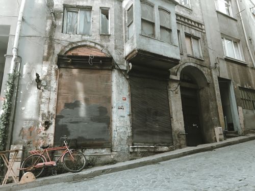 Free An abandoned building on a steep street with a vintage bicycle parked in front, creating an urban decay aesthetic. Stock Photo