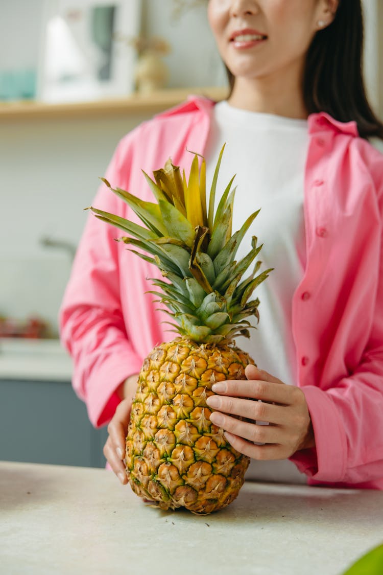 Person In Pink Long Sleeves Holding A Pineapple Fruit