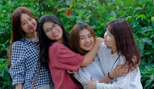 四名年轻女性在户外微笑相拥，传递着友谊与幸福