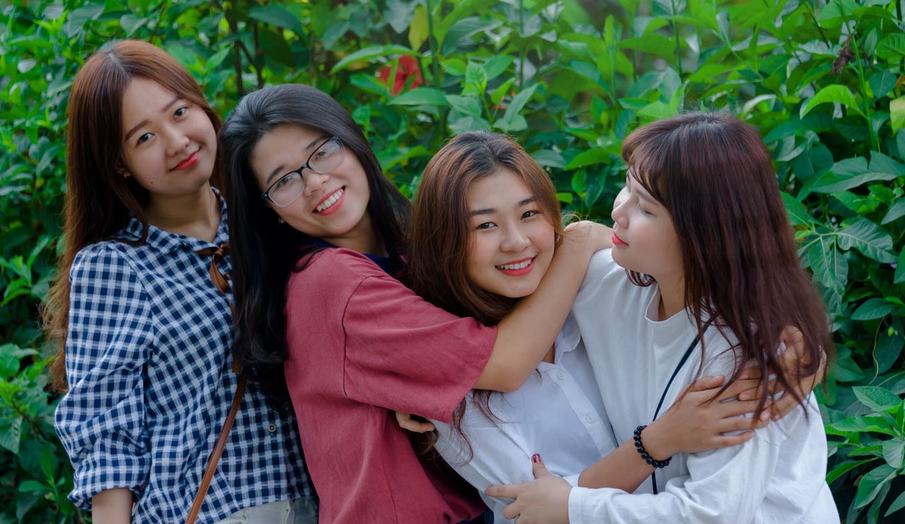 four young women smiling and embracing outdoors conveying friendship a