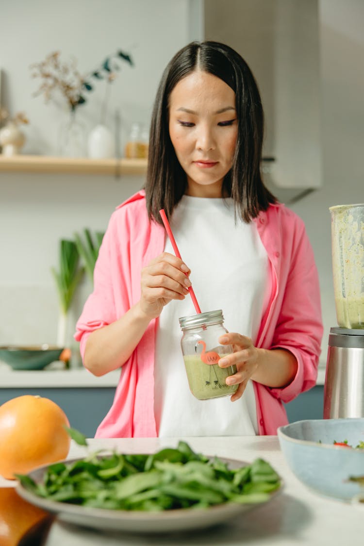 Woman In Pink Long Sleeves Mixing A Drink On A Clear Glass 