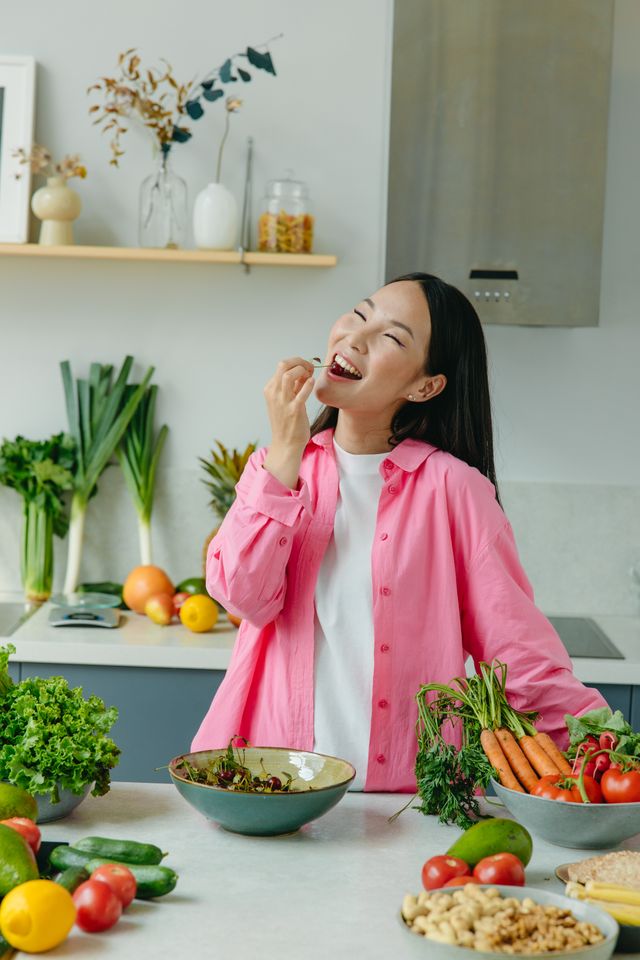Woman enjoying fresh vegetables in a bright kitchen