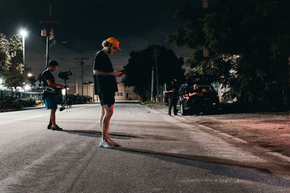 A camera crew sets up under streetlights for an outdoor nighttime film shoot on a quiet city street.