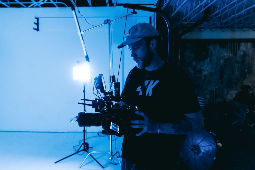 Videographer operating a camera in a blue-lit studio — photo by Kyle Loftus on Pexels