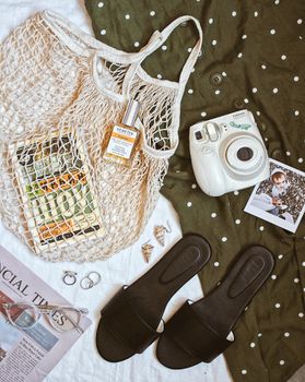 Top view of trendy accessories including mesh bag, camera, perfume, and more on polka dot dress.