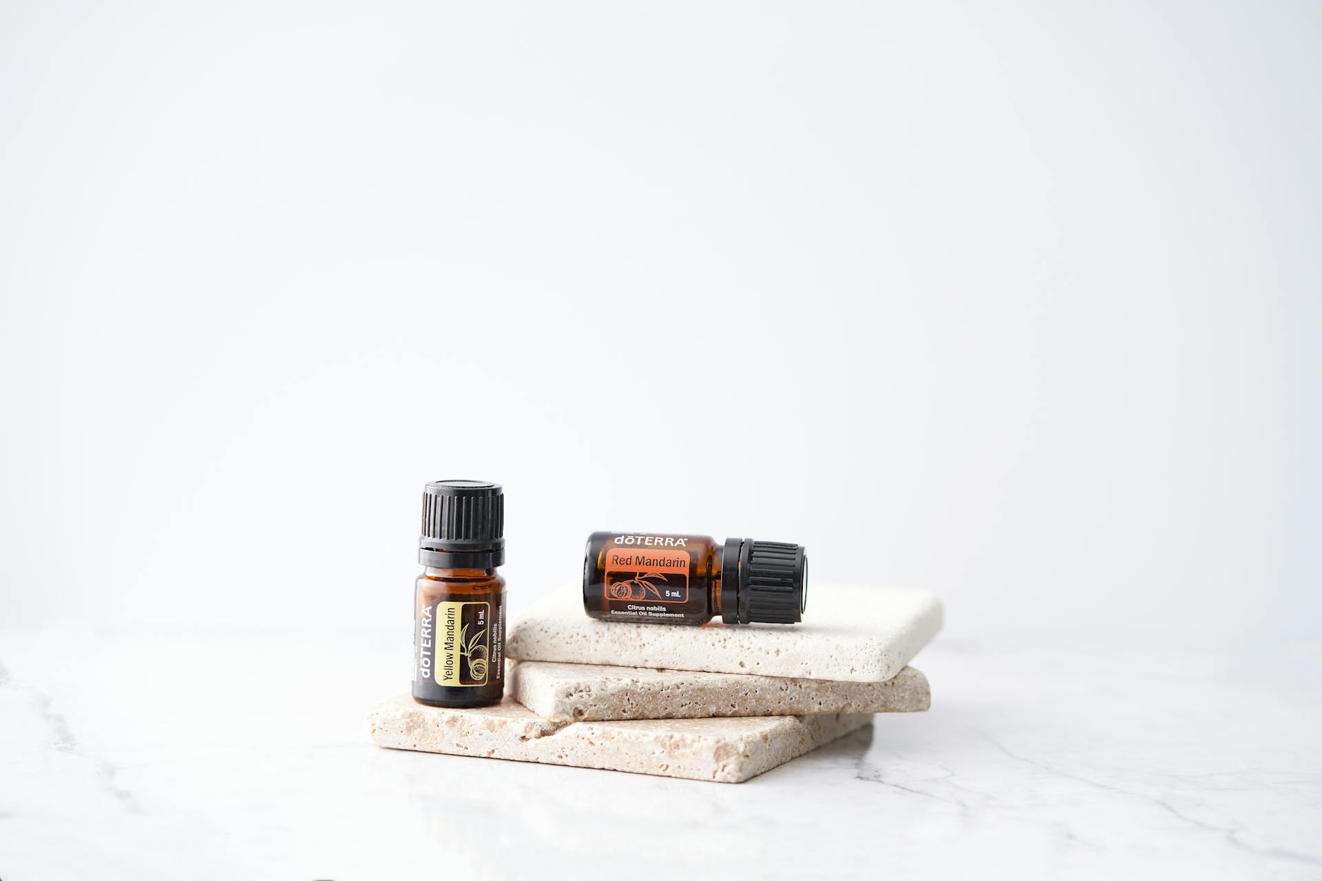 Close-up of essential oil bottles on a stone slab with a white background.