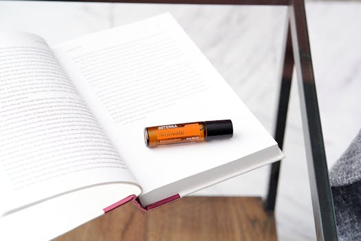 Essential oil bottle on an open book on a glass table captures a relaxing atmosphere.