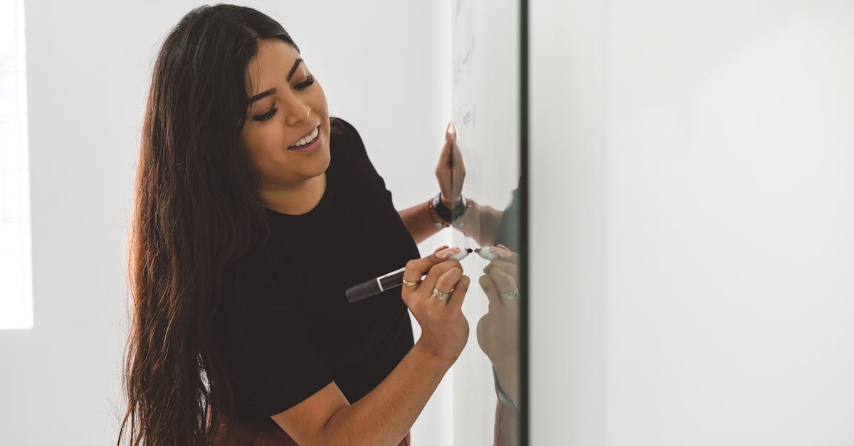 A woman writing on a whiteboard in a bright indoor setting, focusing on workplace productivity.