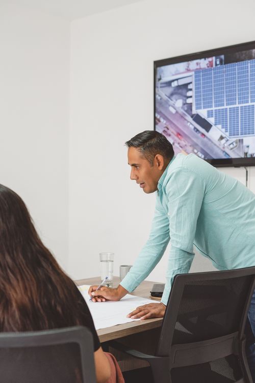 Free Two professionals in an office setting discuss a solar panel project, fostering business collaboration. Stock Photo