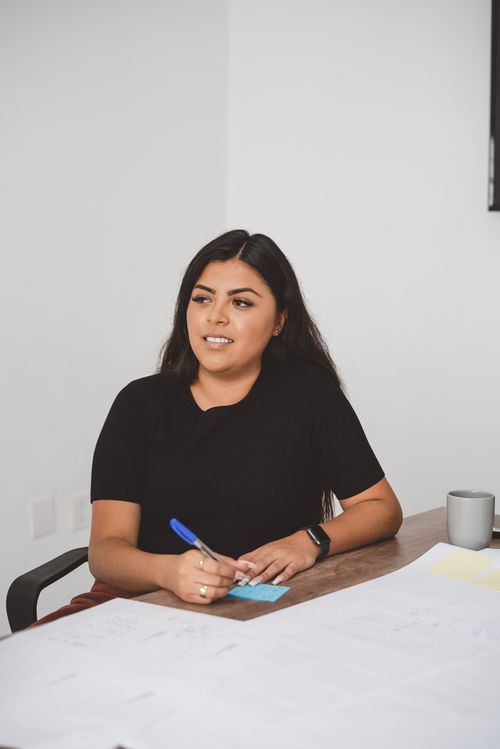 Free Confident woman sitting at a desk in an office, holding a pen. Stock Photo