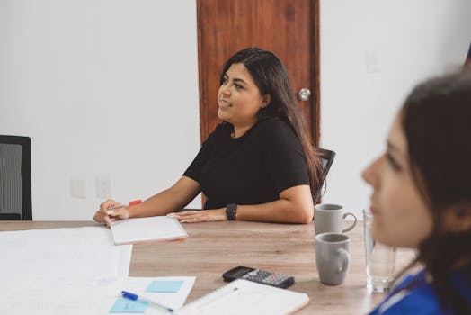 Young women engaged in a collaborative business meeting, focused and attentive.