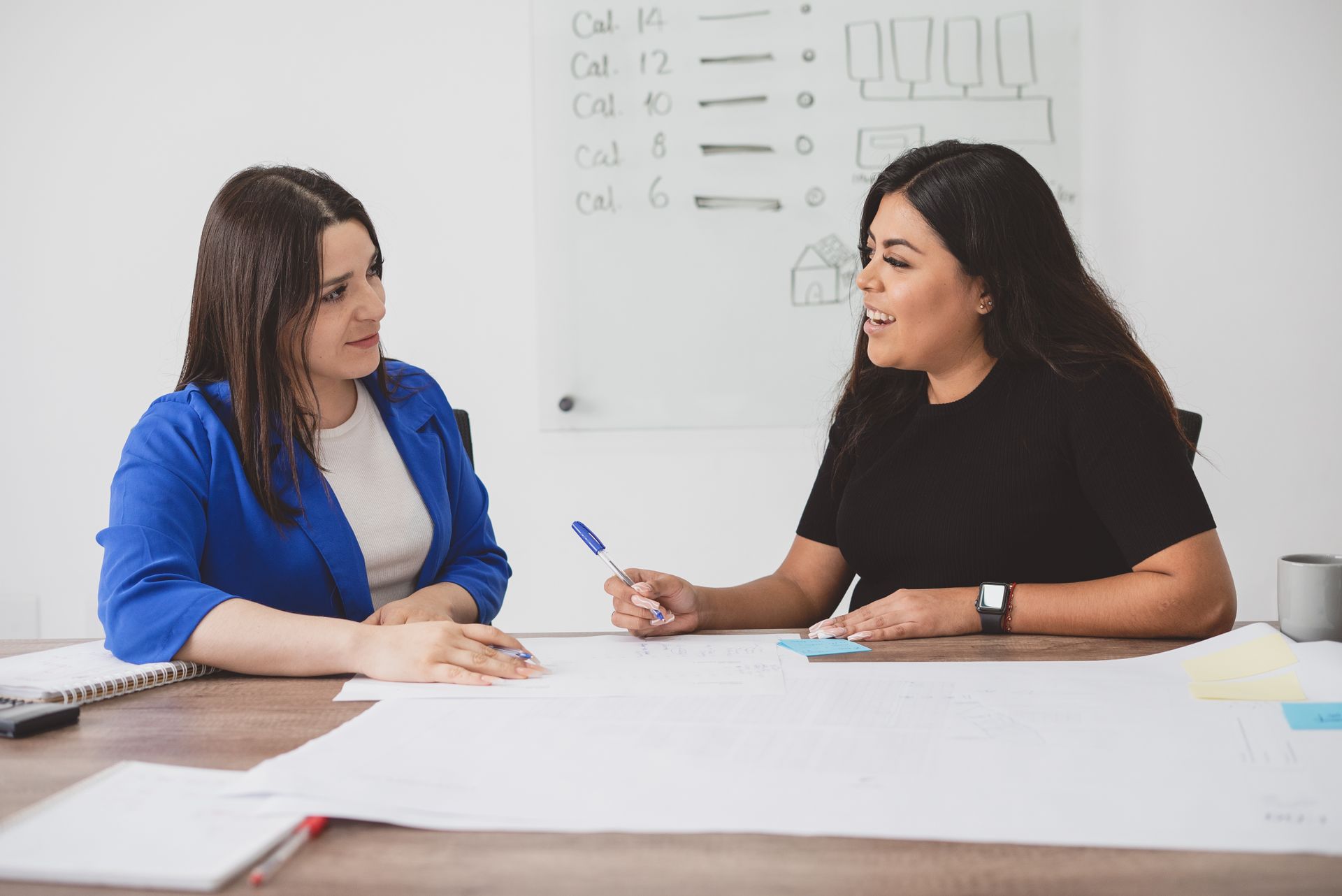 Two women engaging in a business meeting, discussing plans and ideas in a modern office.