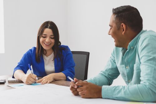 Free Happy colleagues collaborating in an office, writing and discussing ideas. Stock Photo