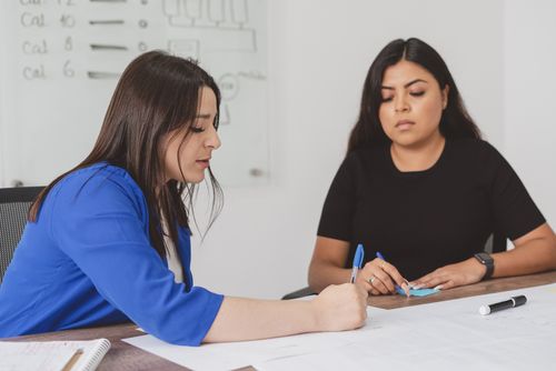 Free Two women discussing paperwork in an office setting, focusing on planning and collaboration. Stock Photo
