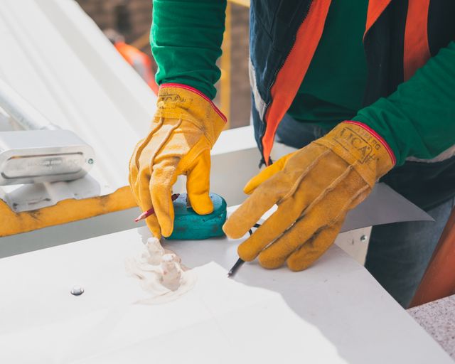 Measuring a roof Worker in gloves measuring on a rooftop in daylight