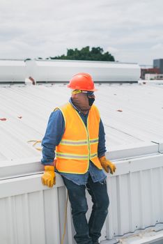 A construction worker wearing PPE gear leaning on a rooftop, showcasing safety at work.