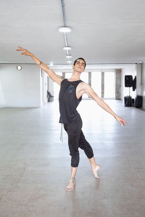 Free A male ballet dancer gracefully performs a pose in a bright dance studio. Stock Photo