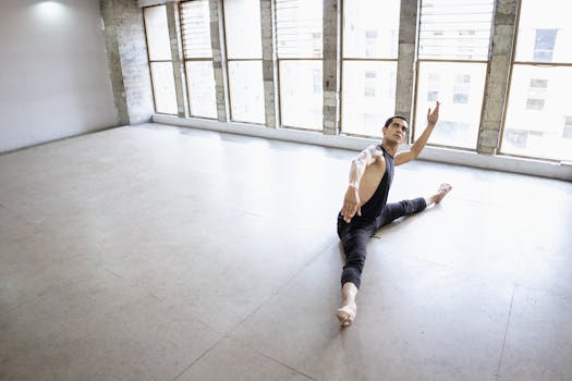 A male ballet dancer rehearses in a spacious dance studio, showcasing flexibility and grace.