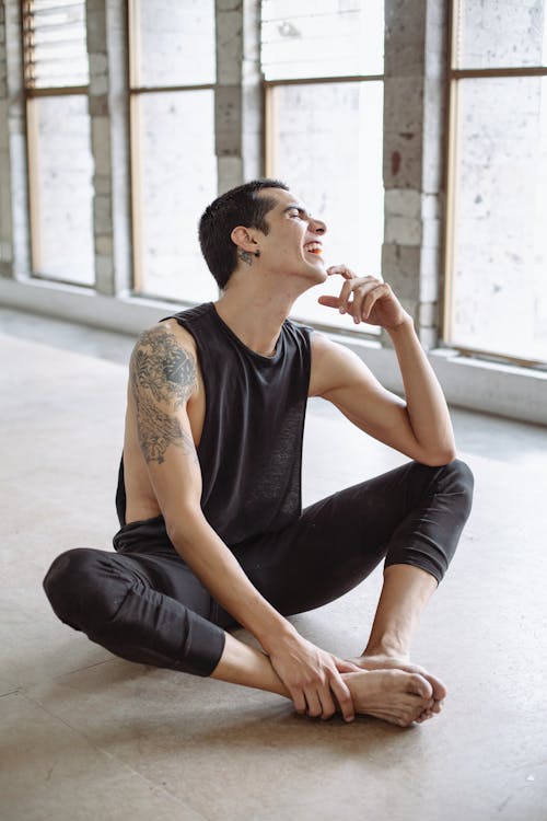 Man in Black Tank Top and Black Pants Sitting on the Floor