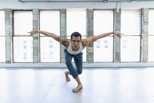 Free A male dancer practicing an expressive ballet pose in an airy dance studio. Stock Photo