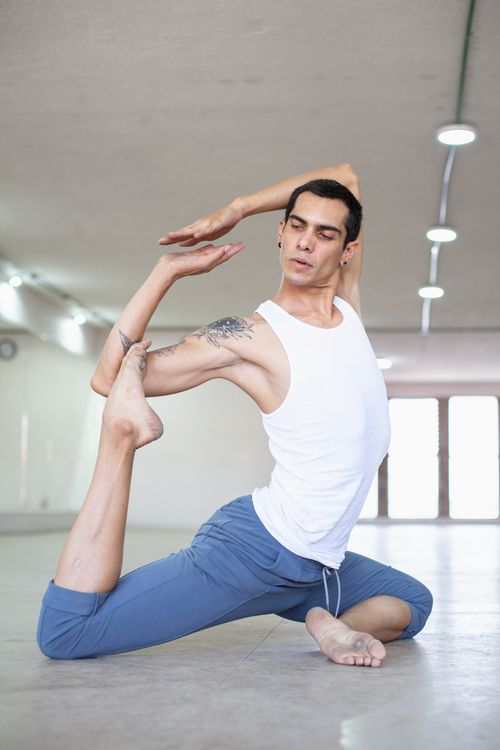 Free Ballet dancer performing a flexible pose during rehearsal in a bright dance studio. Stock Photo