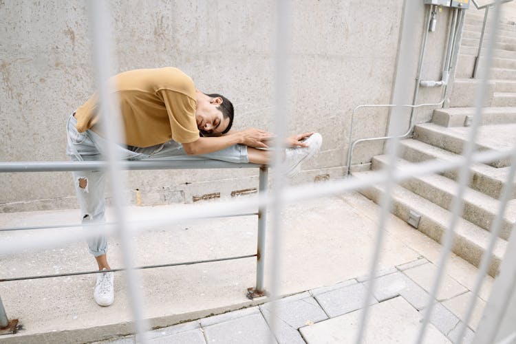 Man Stretching His Legs On The Railings