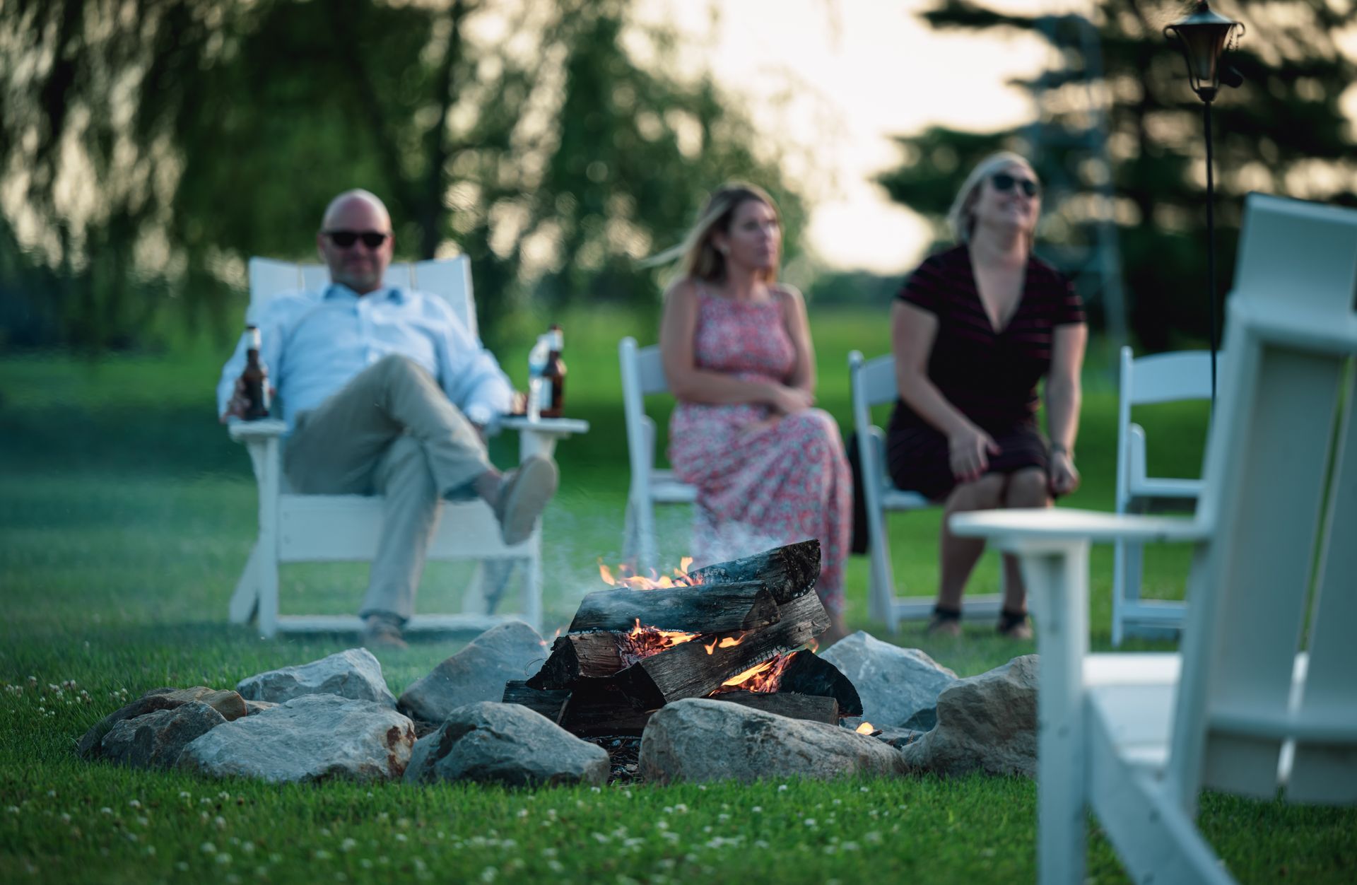 Friends Relaxing on Folding Chairs around Campfire