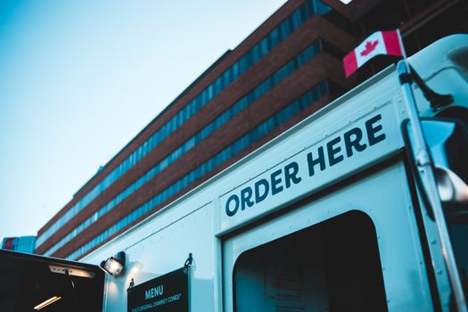Food truck with 'Order Here' sign in front of a building with a Canadian flag.