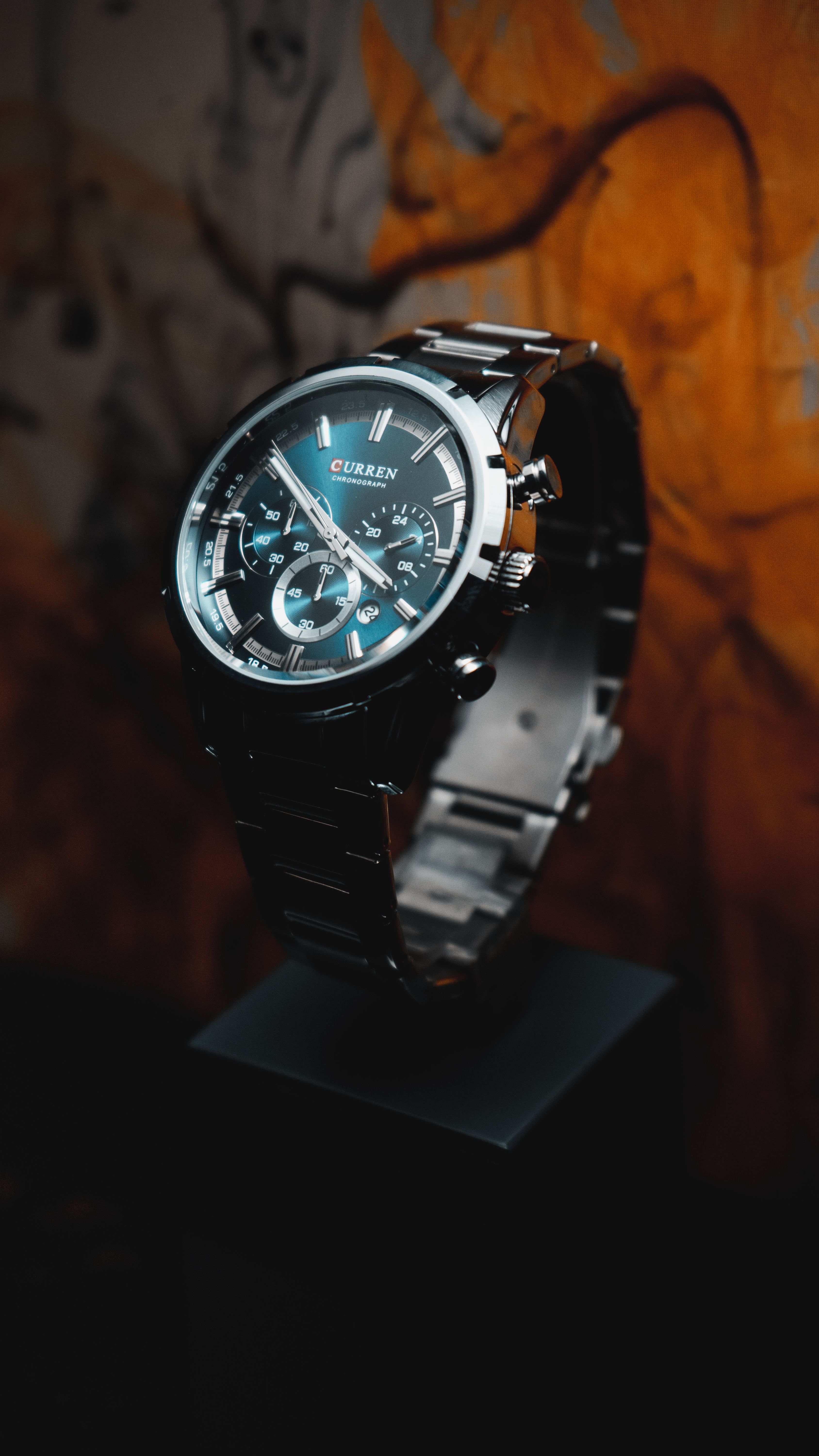 Close-up of a stylish stainless steel chronograph wristwatch on display against a warm background.