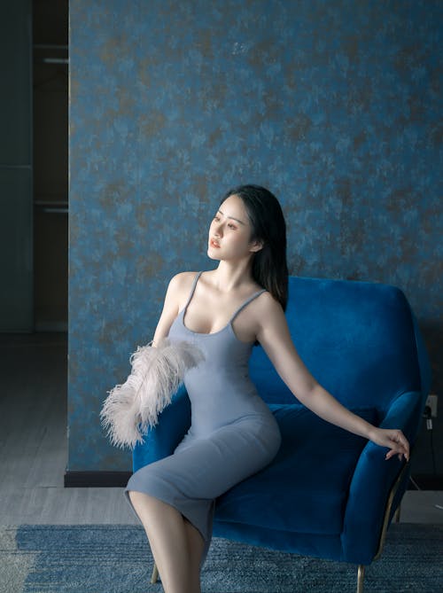 Woman Sitting on Blue Sofa Chair