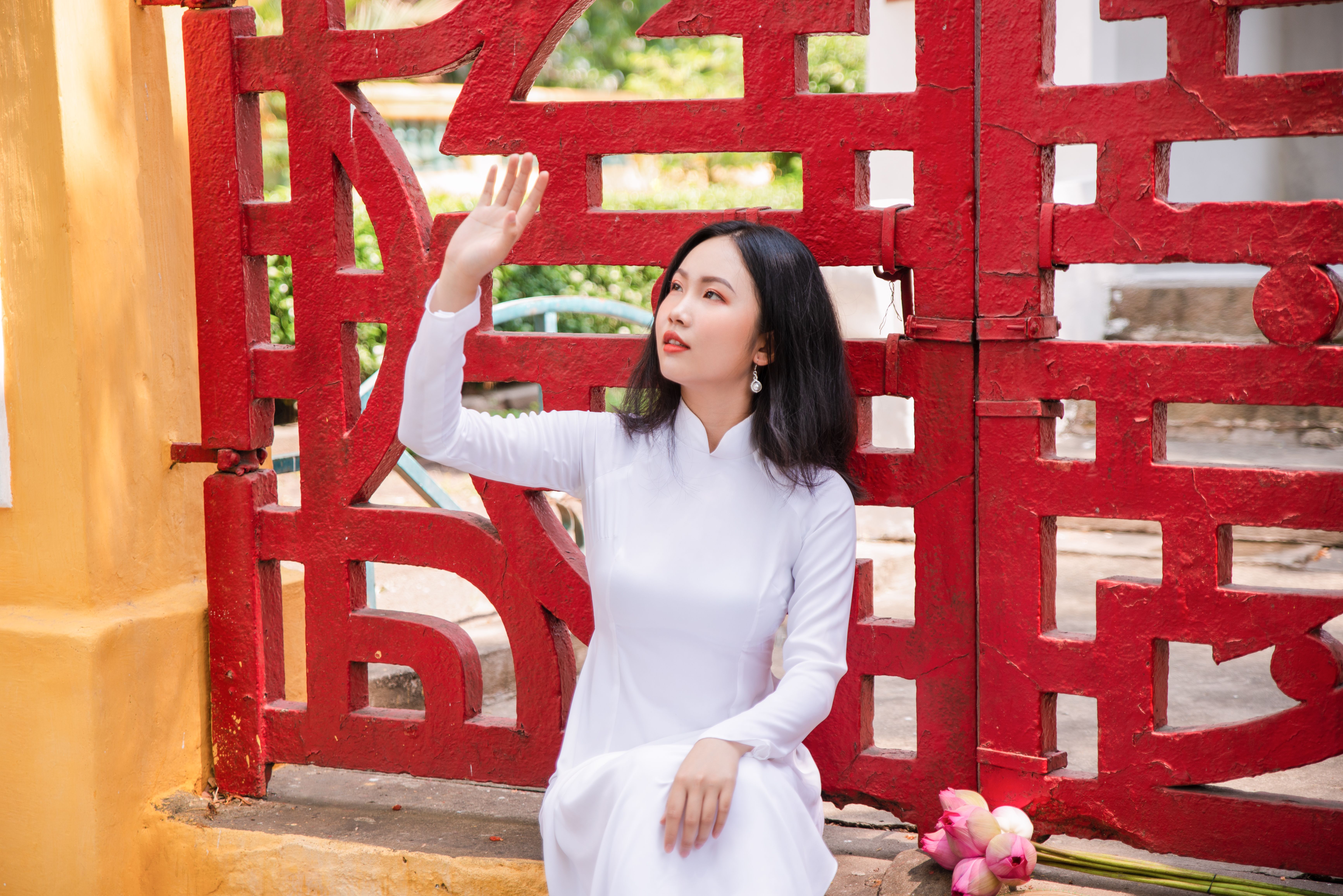 Woman in White Dress Sitting in Front of Red Gate · Free Stock Photo