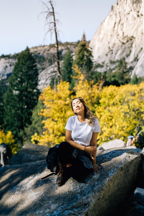 Woman in White Shirt Sitting on a Rock