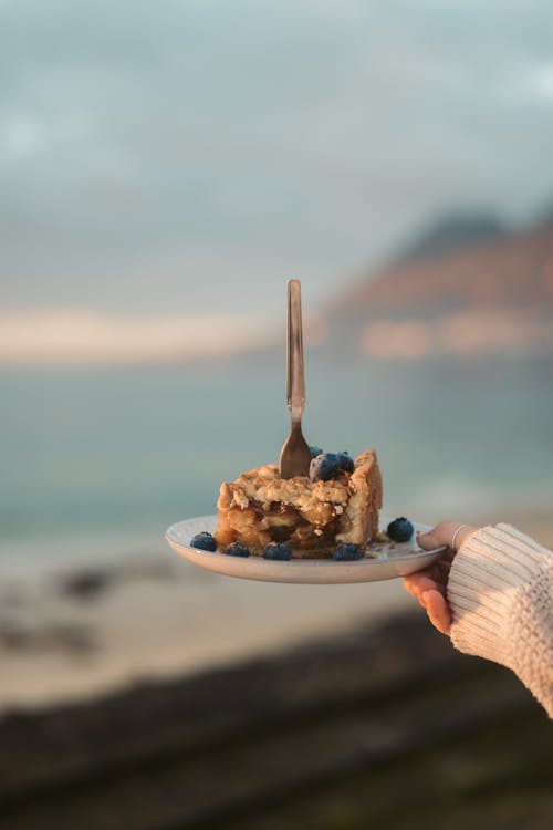 Hand Holding Cake with Fruit and Fork