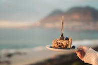 海滩上用叉子拿着蓝莓派片的风景