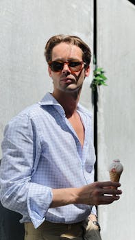 A man in sunglasses enjoys an ice cream cone outdoors, creating a cool, relaxed vibe.
