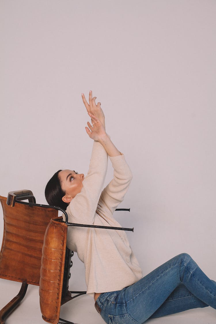 A Woman Reaching Up Beside A Chair