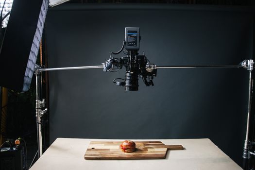 Overhead view of a food photography setup capturing a burger on a wooden board.