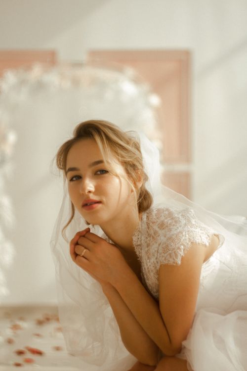 Free Romantic portrait of a bride in a sunlit indoor environment, wearing lace attire. Stock Photo