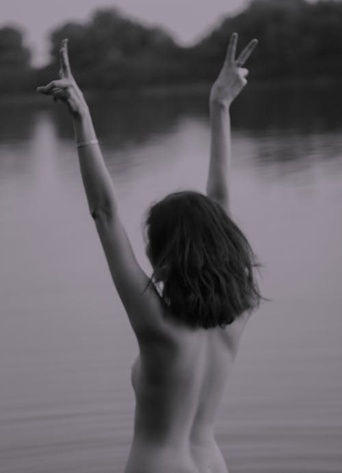 Grayscale Photo of a Naked Woman Doing Peace Sign