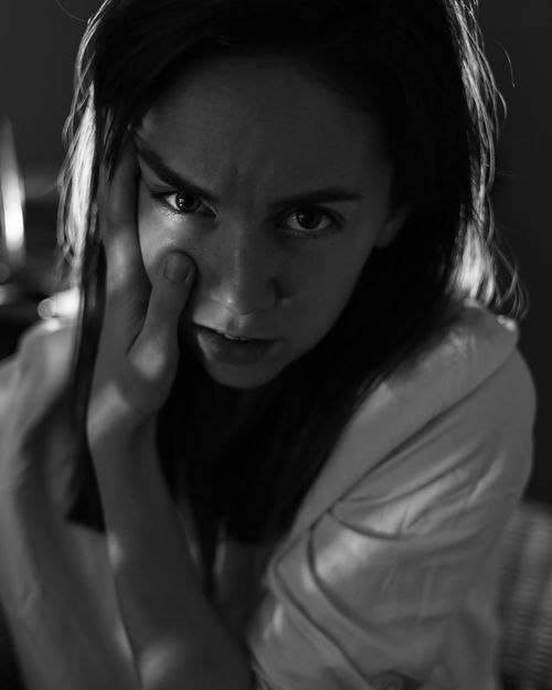 Free Introspective monochrome portrait of a woman with hand on cheek in dim light. Stock Photo