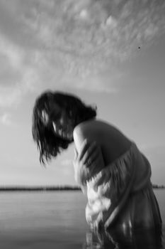 Blurry black and white photo of a woman near water, evoking a dreamy, artistic feel.