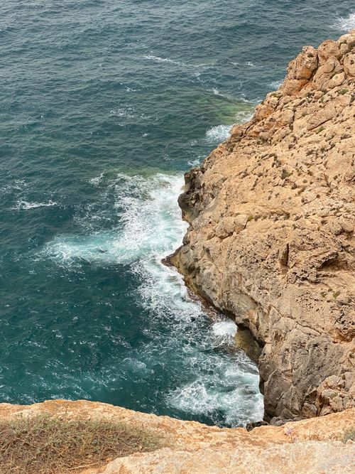 Free A stunning view of a rocky coastline with waves crashing below, showcasing nature's raw beauty. Stock Photo