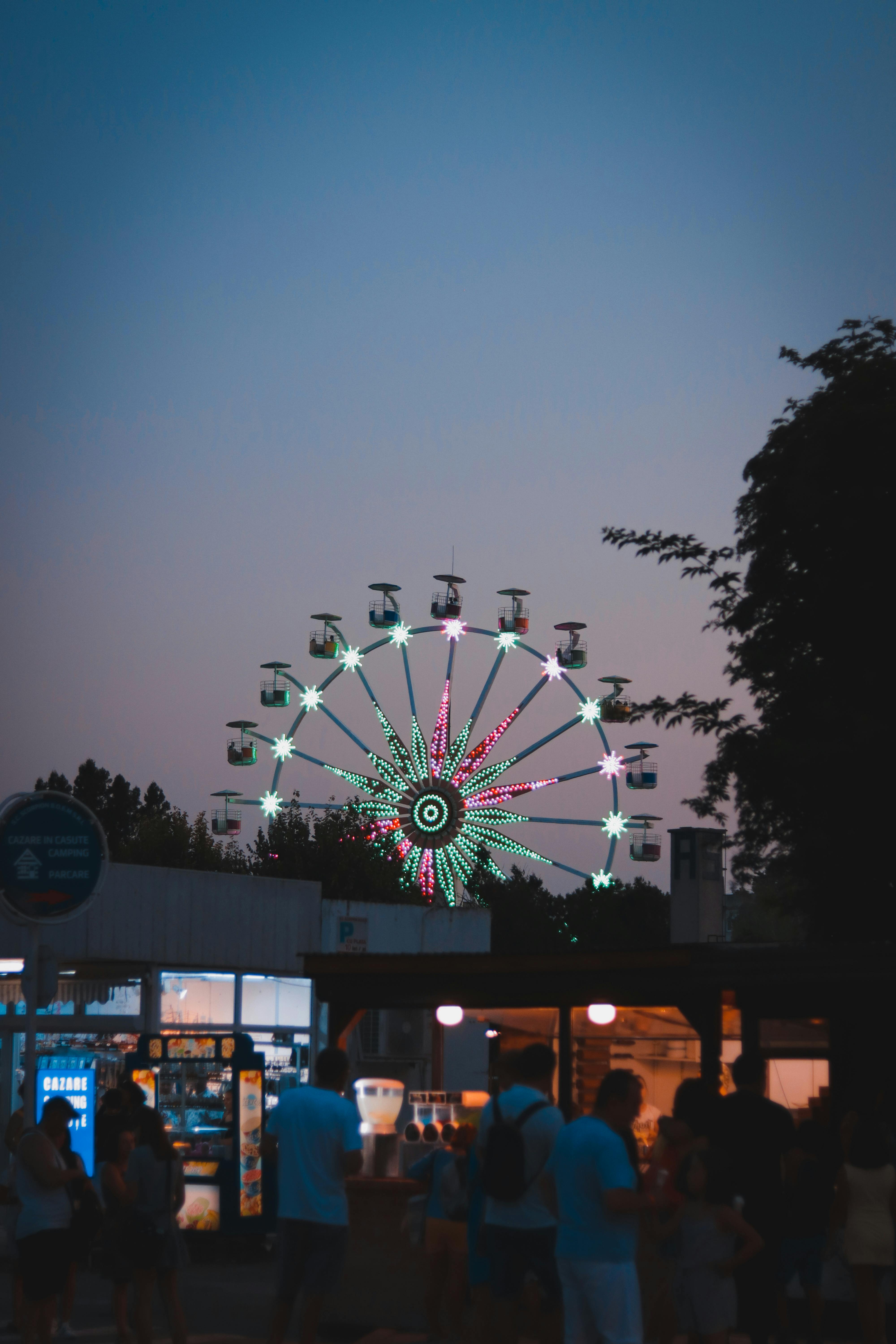 A lively ferris wheel lights up the evening sky at an amusement park, showcasing a fun and colorful view.